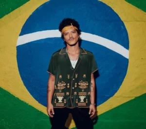 Foto de Bruno Mars atrás de uma pintura da bandeira do Brasil